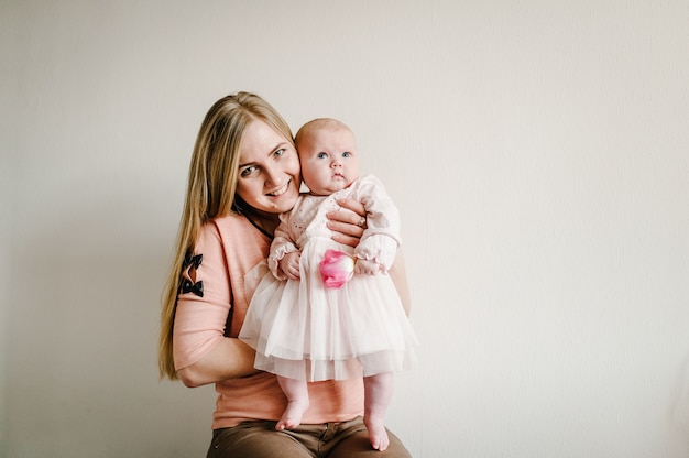 Greeting for a mother with the newborn baby girl who holding the flower. Mother's Day. Happy family portrait, concept of a family holiday.