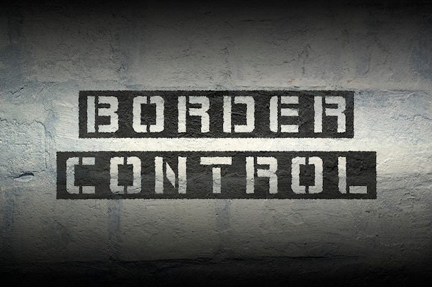 Grenscontrole stencildruk op de grunge witte bakstenen muur