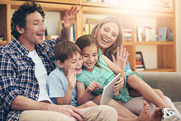 Grensoverschrijdend verbinden met slimme technologie Shot van een gelukkig gezin dat samen thuis een videogesprek voert op hun digitale tablet