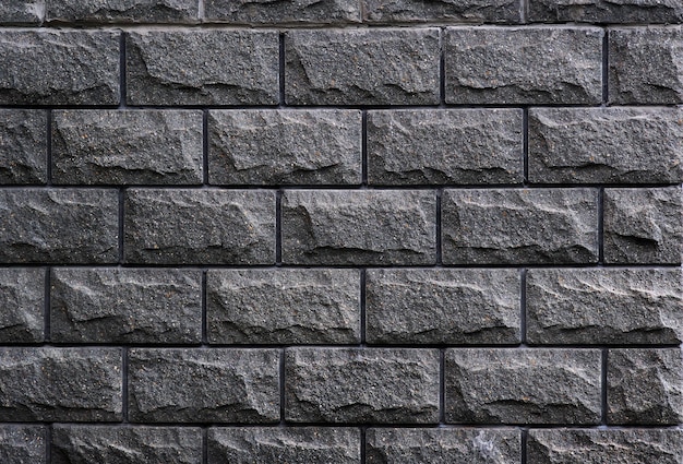 A grey brick wall with a rough textured surface.
