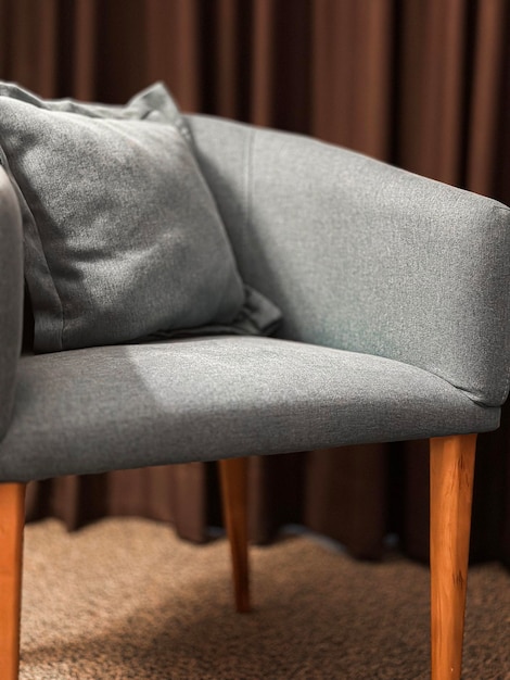 Photo a grey chair with a pillow on it and a brown curtain behind it.