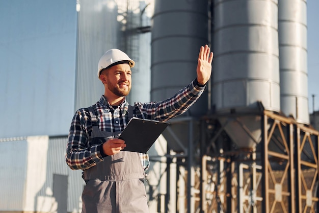 In grey clothes Construction worker in uniform is outdoors near the factory