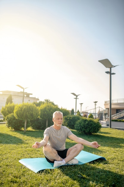 Uomo dai capelli grigi che medita nella posa del loto con le mani in gyan mudra