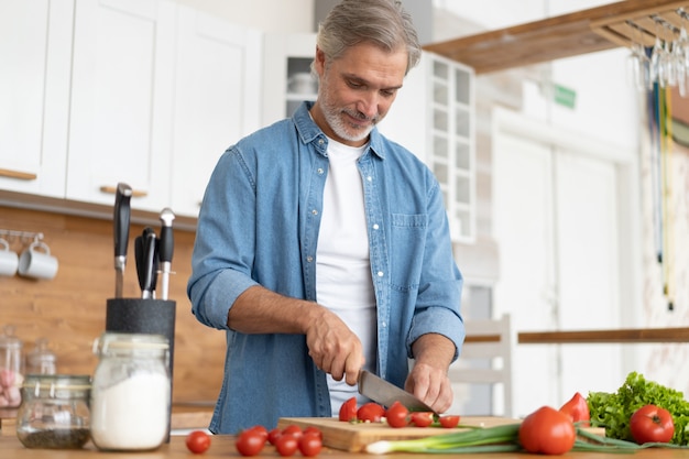 grey-haired mature handsome man preparing delicious and healthy food in the home kitchen.