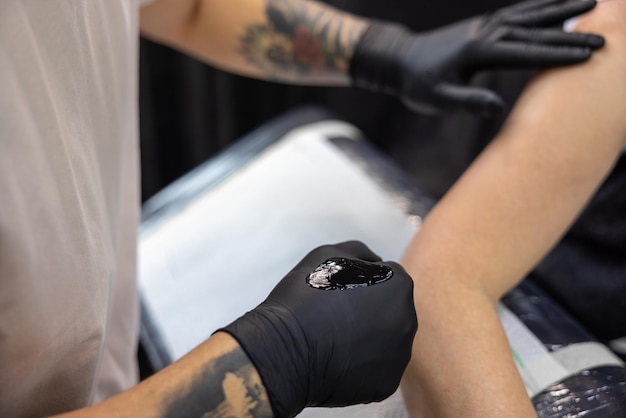 Grey-haired woman getting a tatto in the tattoo salon