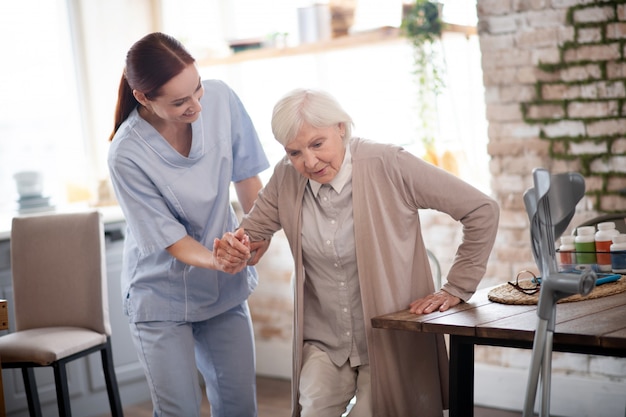 Grey-haired woman trying to walk after surgery