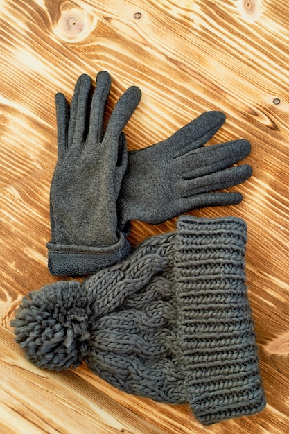 Grey hat and gloves knit on a wooden surfaceThe concept is to keep warm in autumn or winter day