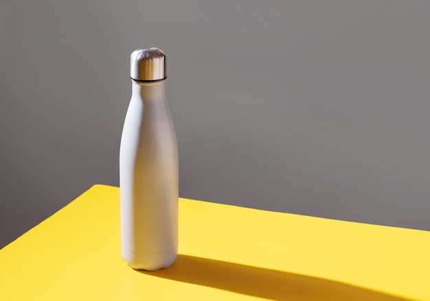 Grey insulated bottle on grey and yellow background close up