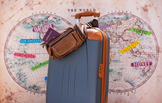 Foto bagaglio grigio pronto per il viaggiatore del mondo, le vacanze e il concetto di libertà - mappa del mondo in background