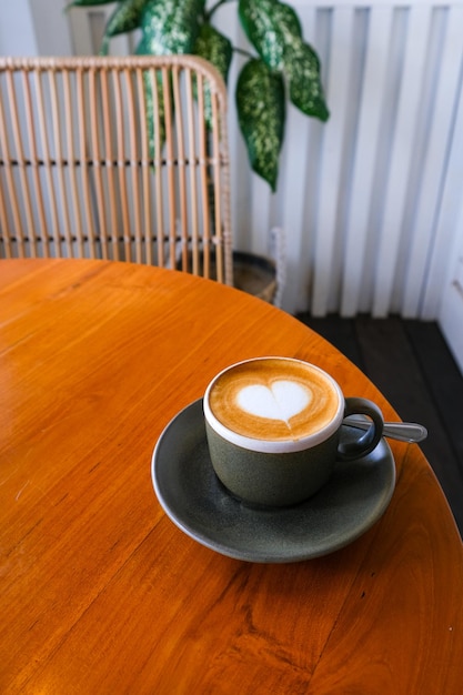 Grey mug of cappuccino on wooden background with beautiful latte art of heart shape