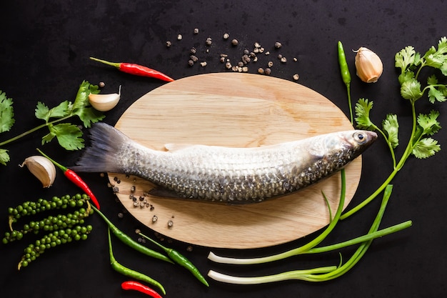 木の板にボラの新鮮な魚と準備された料理の食事を飾る