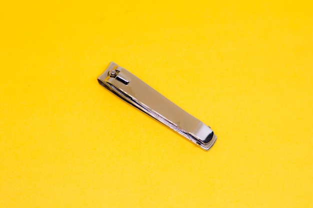 A Grey Nail Clipper in The Center of Yellow Background