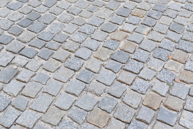 Grey old stone pavement top view o granite cobblestone road