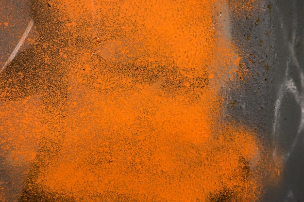 Grey plaster wall with abstract orange graffiti spray paint shape