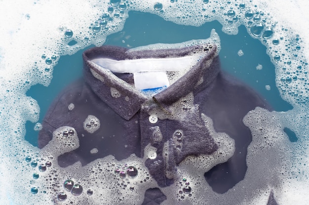 Photo grey polo shirt soak in powder detergent water dissolution. laundry concept