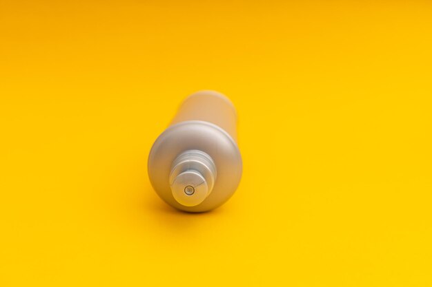 Grey shampoo bottle on a yellow background