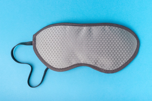 Photo grey sleep mask on blue background close-up, top view