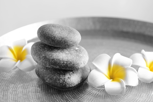 Grey spa stenen met plumeria bloemen close-up