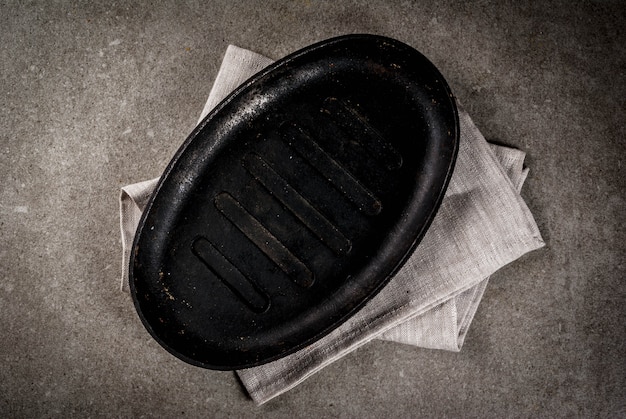 Grey stone culinary background with empty black pan