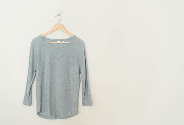 grey t-shirt hanging with wood hanger on wall