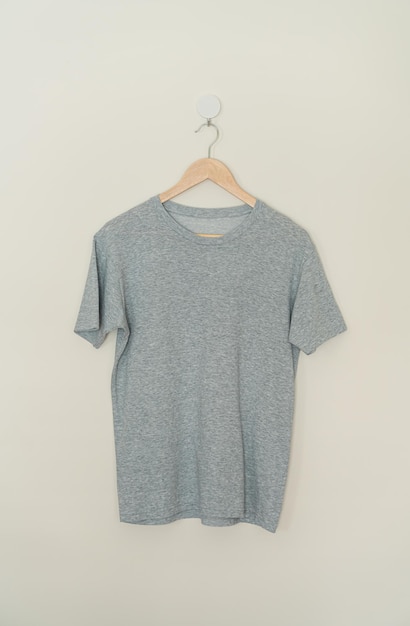 Photo grey t-shirt hanging with wood hanger on wall