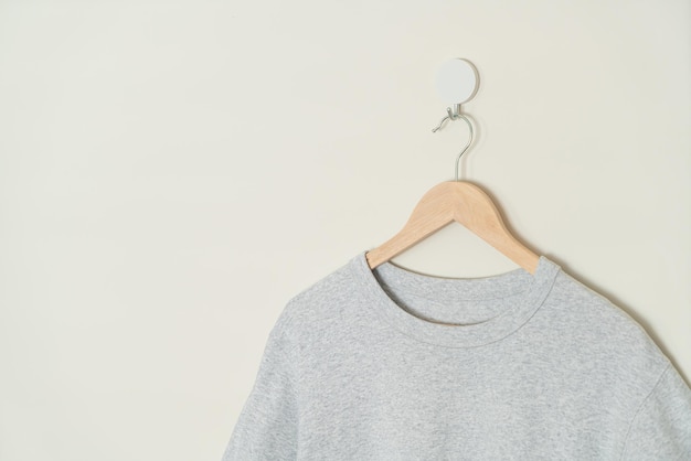 grey t-shirt hanging with wood hanger on wall