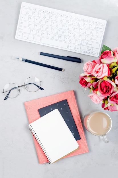 Foto tavolo scrivania grigio sul posto di lavoro con notebook, spazio vuoto vuoto, forniture, bicchieri e tazza di caffè.