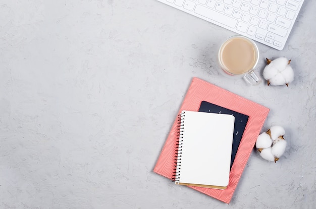 Tavolo scrivania grigio sul posto di lavoro con notebook, spazio vuoto vuoto, forniture, bicchieri e tazza di caffè.