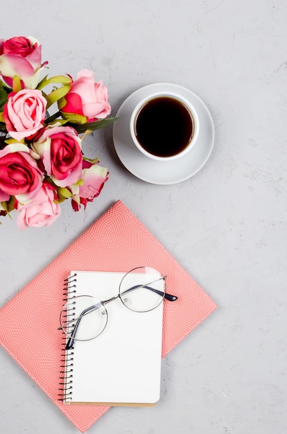 Grey workplace desk table with notebooks, empty blank, supplies, glasses and cup of coffee