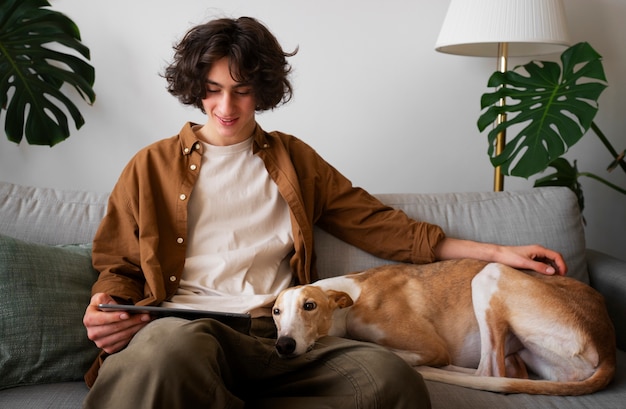 Greyhound dog with male owner on couch at home