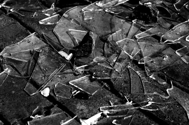 Greyscale shot of broken glass on a ground