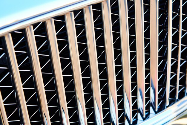 Grid of car with sunflare. Radiator grille. Metal close-up texture background. Chrome grill of big powerful engine macro.