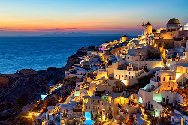 Griekenland vakantie achtergrond Beroemd iconisch Oia dorp met traditionele witte huizen en windmolens tijdens kleurrijke zonsondergang Santorini eiland Griekenland