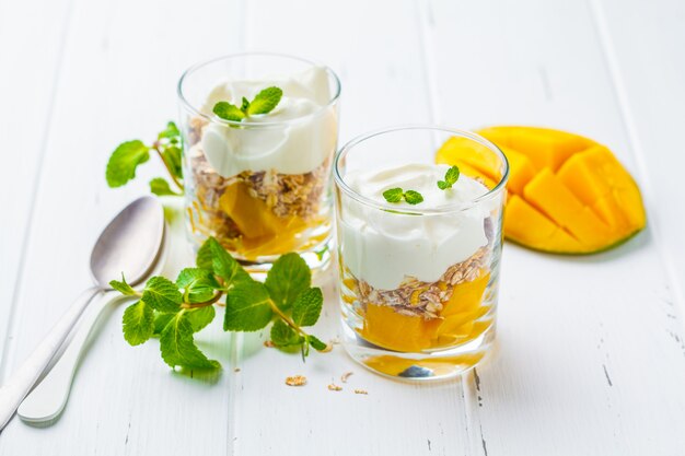 Grieks de granolparfait van de yoghurtmango in een glas op wit hout