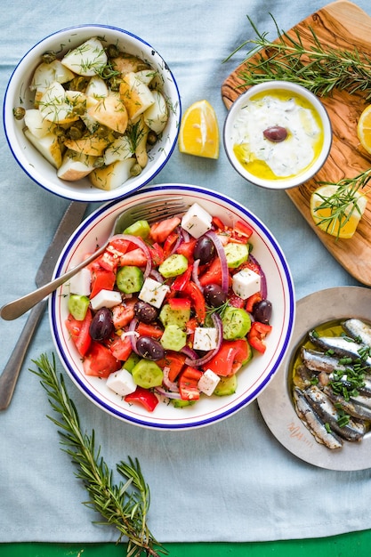 Grieks eten tafelscène bovenaanzicht Verscheidenheid aan items, waaronder griekse salade komkommerdip Tzatziki Ansjovisfilets citroenaardappelen