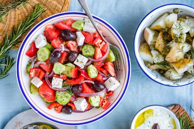 Grieks eten tafelscène bovenaanzicht Verscheidenheid aan items, waaronder griekse salade komkommerdip Tzatziki Ansjovisfilets citroenaardappelen