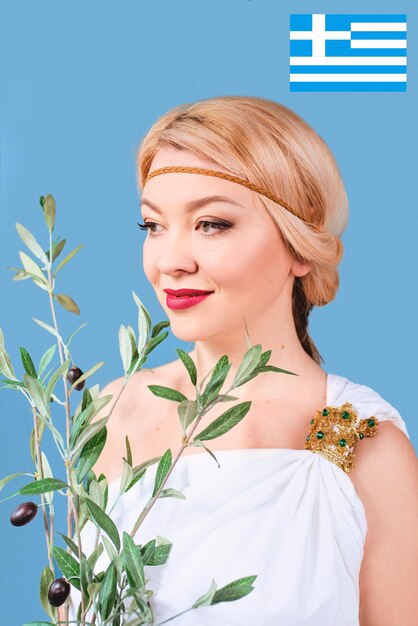 griekse blonde vrolijke vrouw in nationale klederdracht met nep olijftak in haar handen
