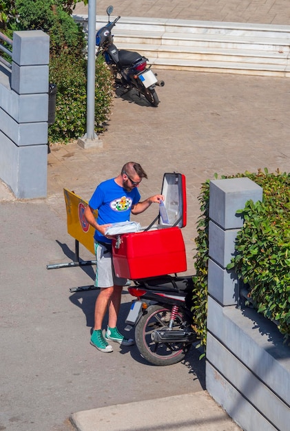 Griekse postkoerier op een motorfiets met documenten op de hoofdstraat van de stad in Griekenland