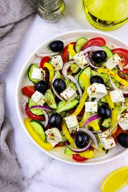 Griekse salade close-up met olijfolie, kruiden en een schijfje citroen op grijze achtergrond. Gezond eten