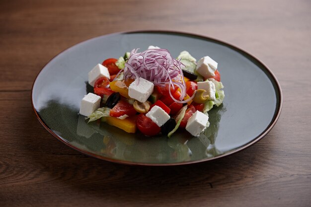 Griekse salade in een keramische plaat op een houten donkere tafel.