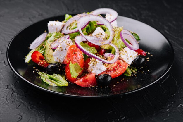 Griekse salade in zwarte kom op steen
