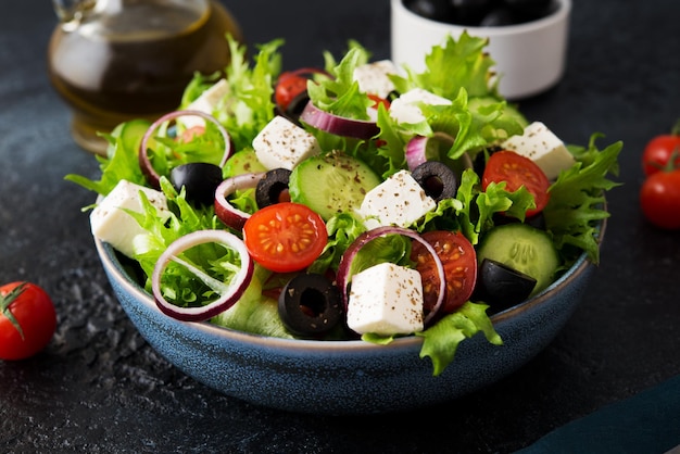 Griekse salade met tomaten, komkommers, olijven en fetakaas in een bord op een betonnen ondergrond, typisch Griekse keuken, close-up