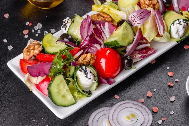 Griekse salade met verse groenten, fetakaas en zwarte olijven. Gezonde salade met cherrytomaatjes, biologische olijven, komkommer, sla en kruiden