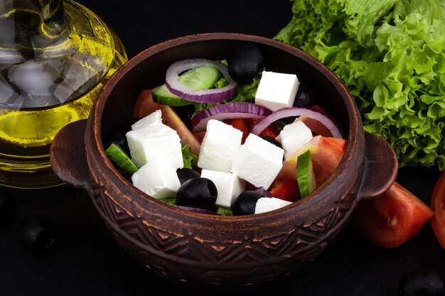 Griekse salade met verse groenten, fetakaas en zwarte olijven op een donkere achtergrond.