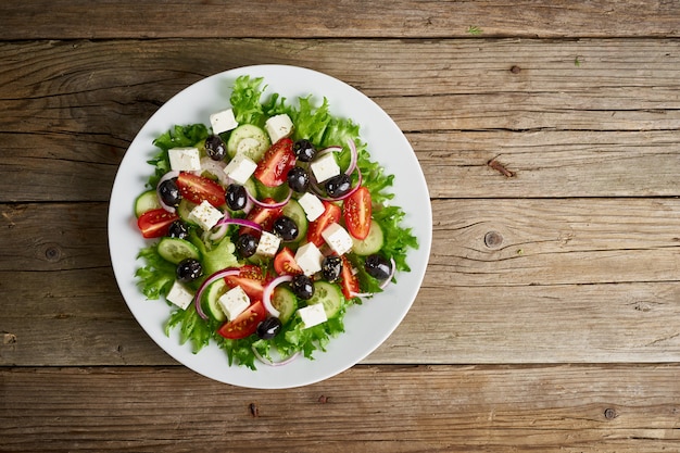 Griekse salade op witte plaat op oude rustieke houten lijst, hoogste mening, exemplaarruimte