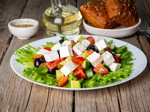 Griekse salade op witte plaat op oude rustieke houten lijst, zijaanzicht