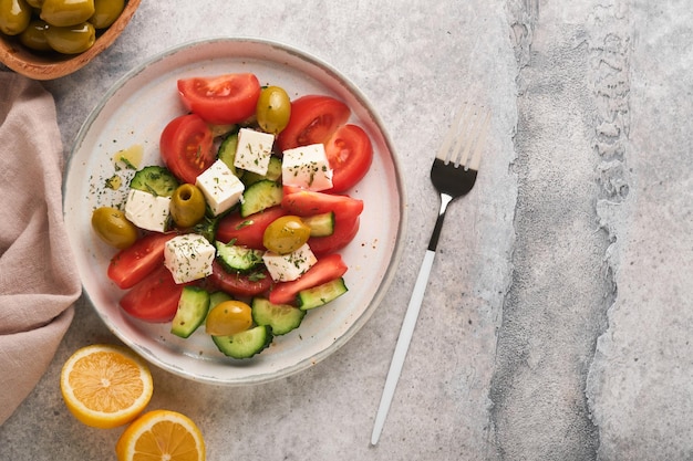 Griekse salade Verse Griekse salade met verse groenten, tomaat, komkommer, groene olijven en fetakaas op een oude grijze betonnen tafelachtergrond Bovenaanzicht