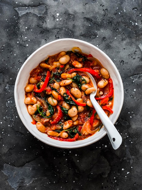 Griekse stijl tomatensaus spinazie paprika bonen gestoofd op een donkere achtergrond bovenaanzicht