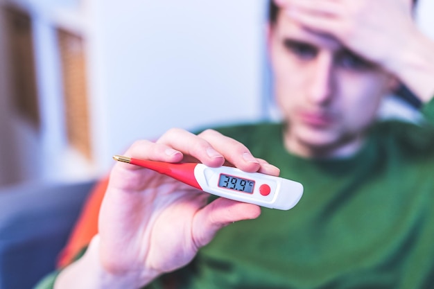 Griep en corona concept Man houdt van dichtbij een koortsthermometer in zijn hand