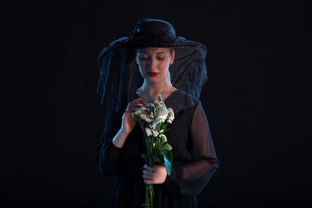 Photo grieving female dressed in black with flowers on black isolated surface death funeral